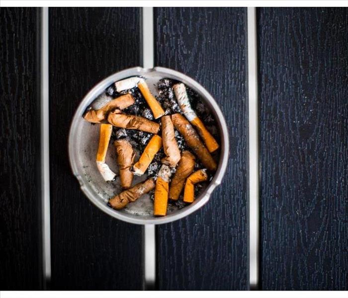 An ashtray with old smoked cigarettes stands on a black table top view, day